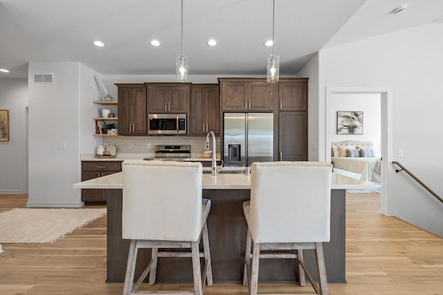 kitchen featuring an island with sink, appliances with stainless steel finishes, light countertops, and pendant lighting