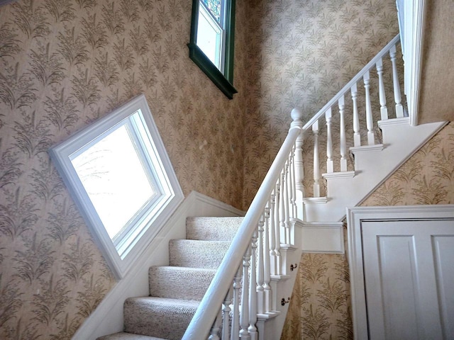 stairway featuring plenty of natural light and wallpapered walls