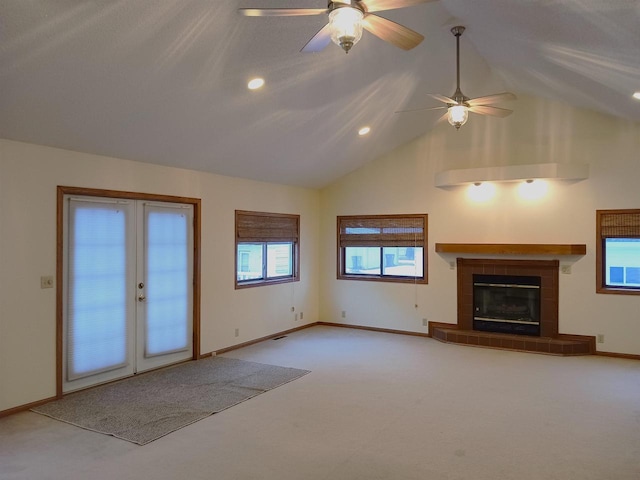 unfurnished living room with high vaulted ceiling, a tile fireplace, light carpet, a ceiling fan, and baseboards