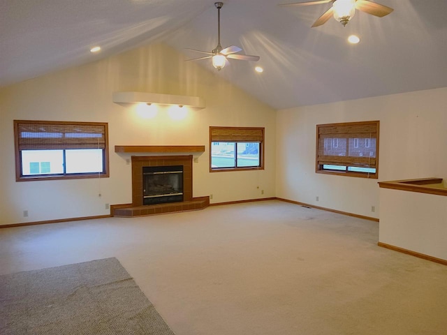 unfurnished living room with light carpet, baseboards, a tiled fireplace, ceiling fan, and high vaulted ceiling