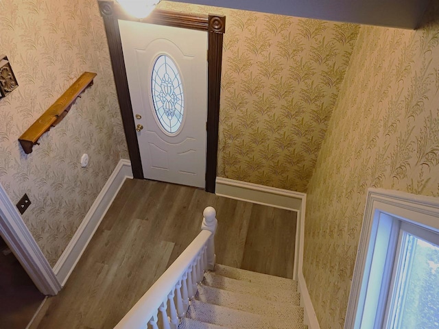 foyer entrance featuring baseboards, wood finished floors, stairs, and wallpapered walls