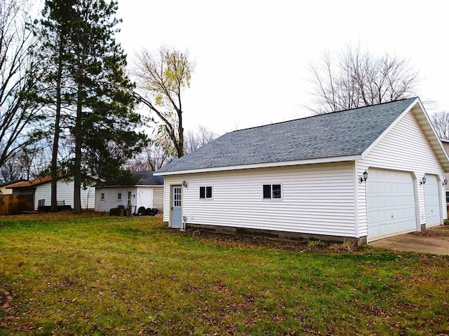 rear view of house with a shingled roof, a lawn, and an outdoor structure