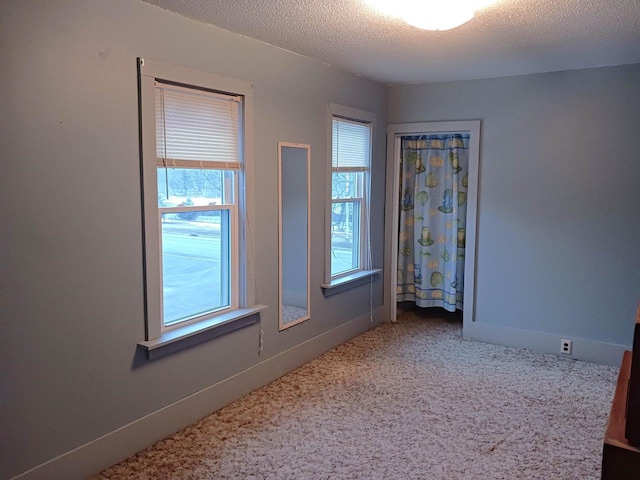 empty room with a textured ceiling and baseboards