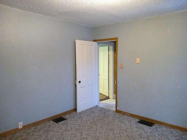 empty room featuring visible vents, light carpet, baseboards, and a textured ceiling