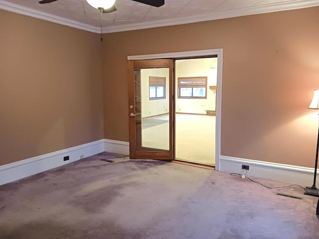 carpeted empty room featuring baseboards, visible vents, ornamental molding, and a ceiling fan