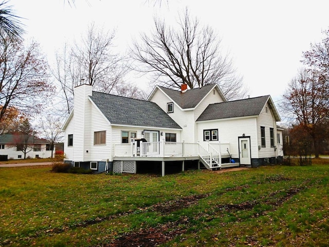 back of house featuring a shingled roof, a chimney, a deck, and a yard