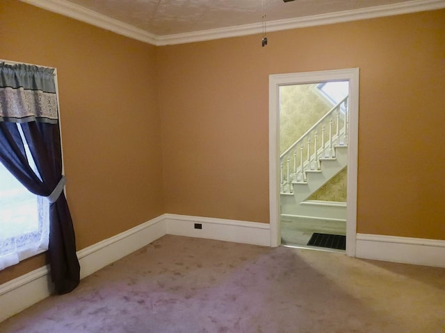 empty room featuring carpet floors, visible vents, baseboards, stairs, and crown molding