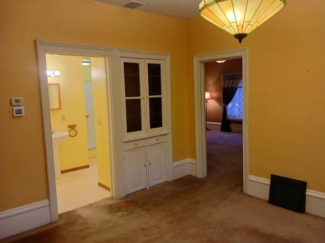 corridor with light carpet, visible vents, and baseboards