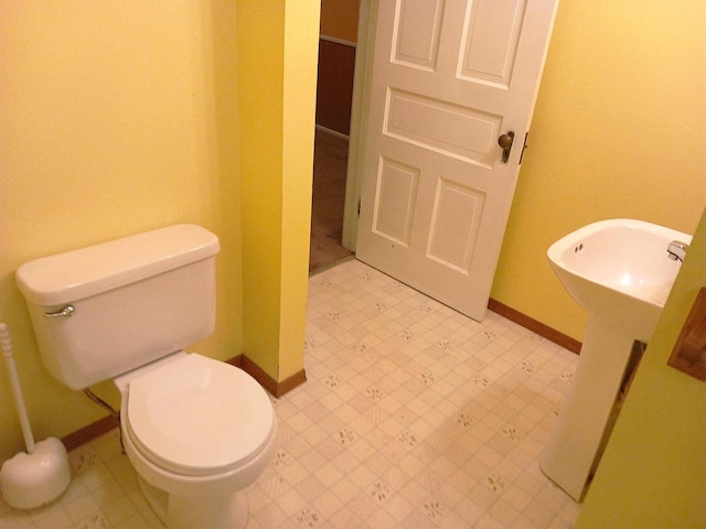 bathroom with baseboards, a sink, toilet, and tile patterned floors