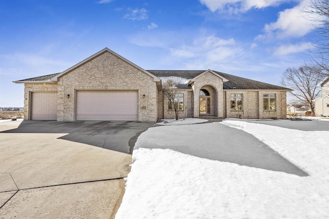 french country home featuring a garage, concrete driveway, and brick siding