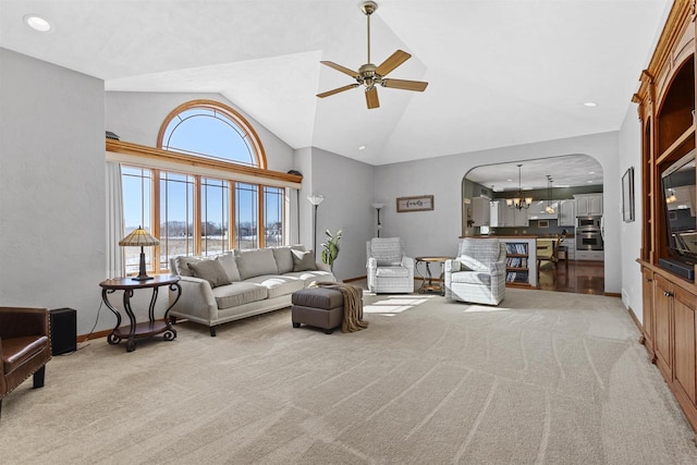 living room with arched walkways, ceiling fan with notable chandelier, light carpet, and baseboards