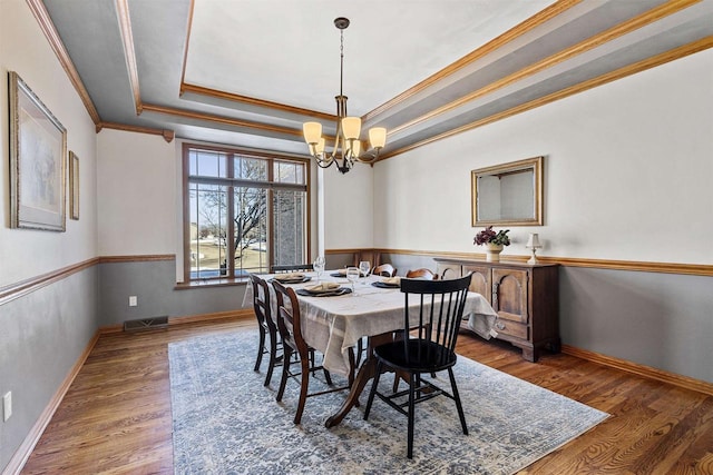 dining space with a tray ceiling, a notable chandelier, visible vents, dark wood-type flooring, and ornamental molding