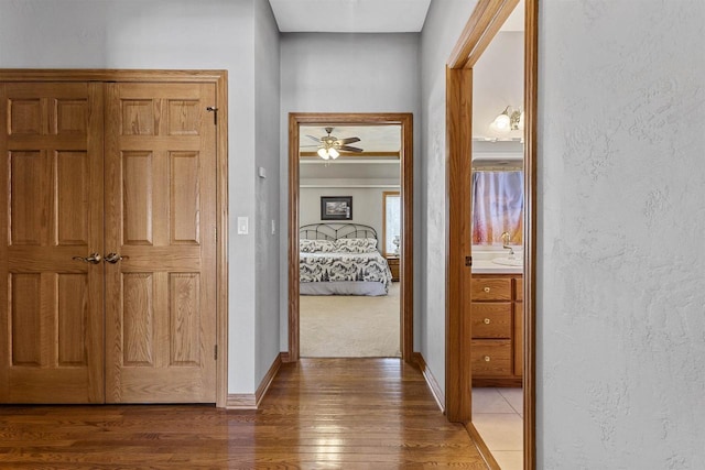 corridor with a textured wall, dark wood finished floors, and baseboards