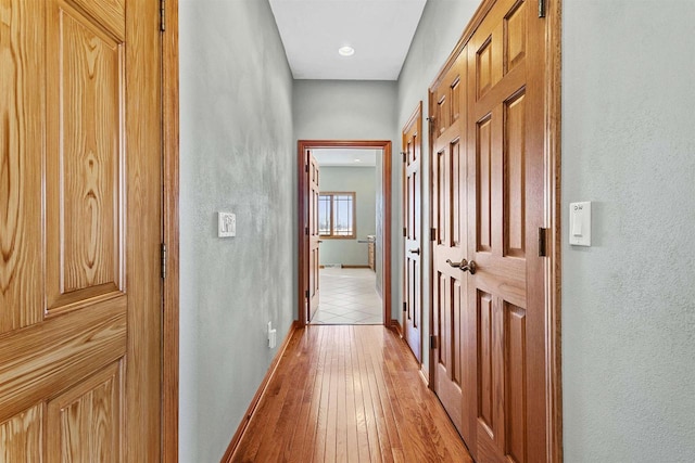 hallway featuring light wood-type flooring and baseboards