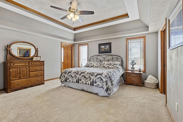 bedroom featuring a raised ceiling, light colored carpet, ceiling fan, and baseboards