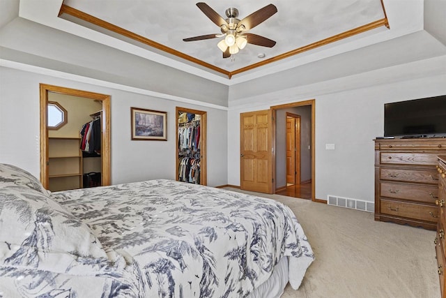 bedroom with a walk in closet, visible vents, and a raised ceiling