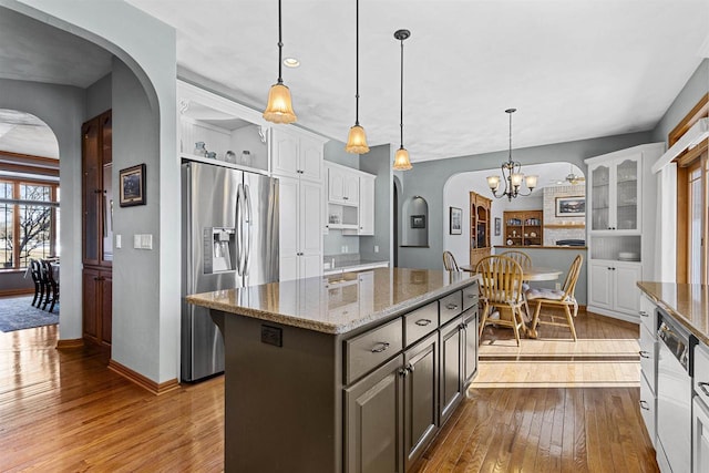 kitchen featuring white cabinetry, stainless steel refrigerator with ice dispenser, light stone counters, and pendant lighting