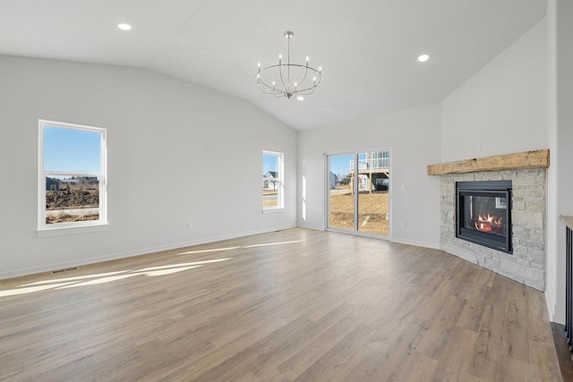 unfurnished living room featuring lofted ceiling, light wood-type flooring, a fireplace, and a notable chandelier