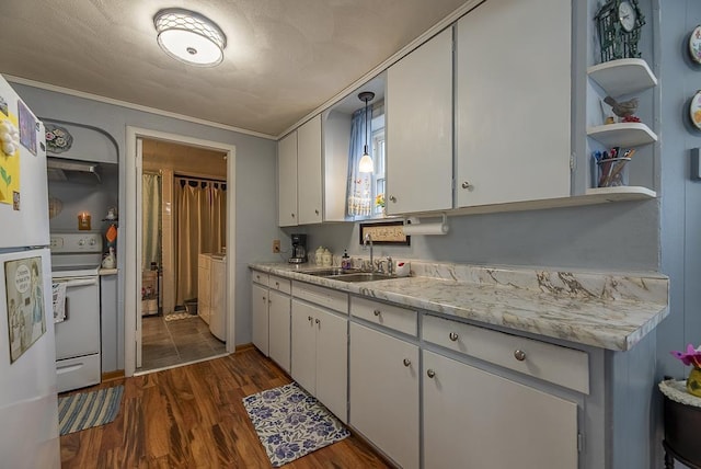 kitchen with white appliances, dark wood-style floors, light countertops, separate washer and dryer, and a sink