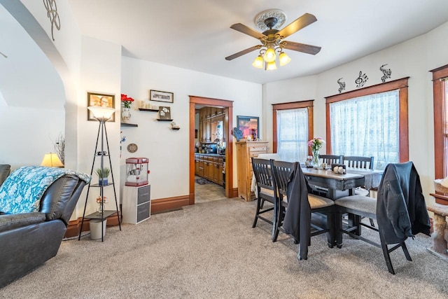 carpeted dining space with ceiling fan and baseboards