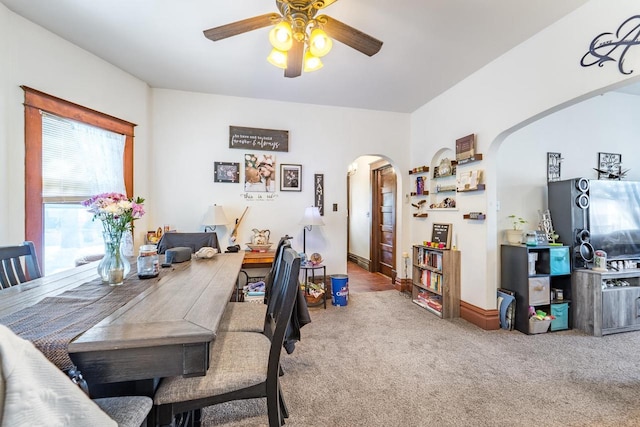 dining space featuring carpet, arched walkways, and a ceiling fan