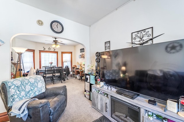 living room featuring a ceiling fan, arched walkways, and carpet flooring