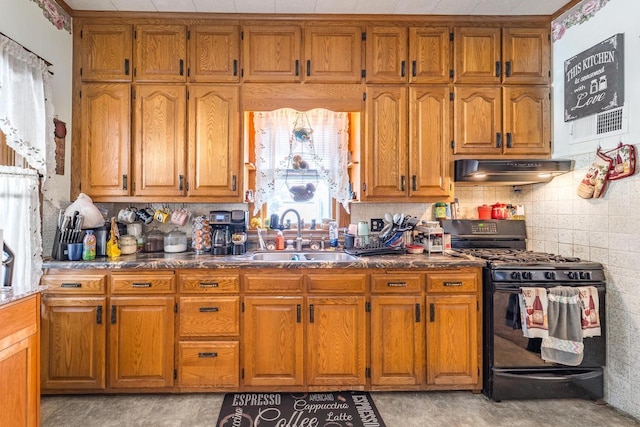 kitchen featuring brown cabinetry, a sink, black range with gas stovetop, under cabinet range hood, and backsplash