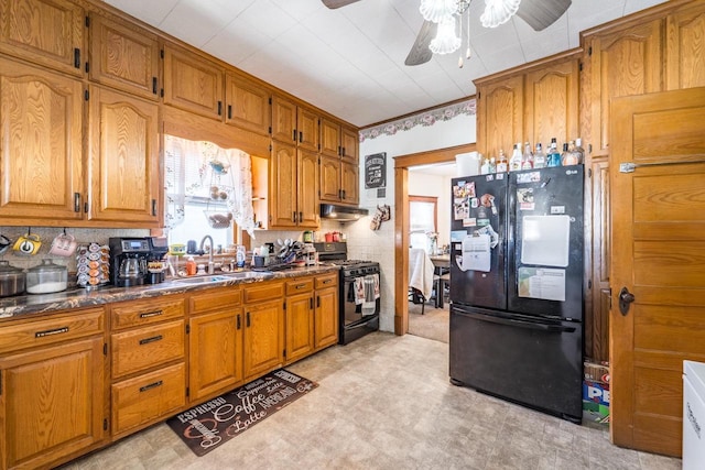 kitchen with black appliances, dark countertops, a sink, and brown cabinets