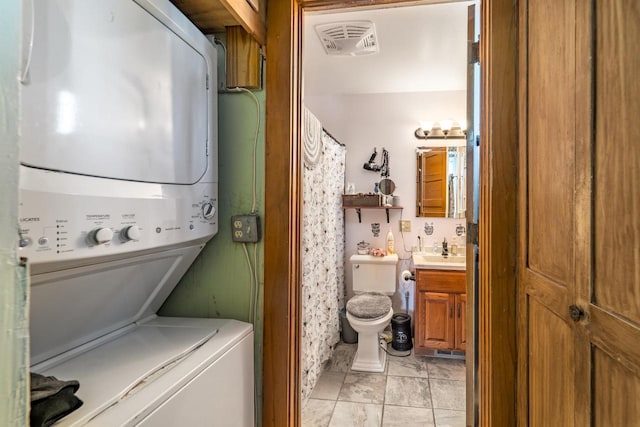 laundry area with stacked washer and dryer, a sink, and visible vents