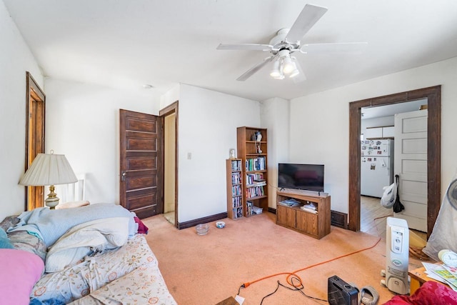 living room featuring baseboards, a ceiling fan, and light colored carpet