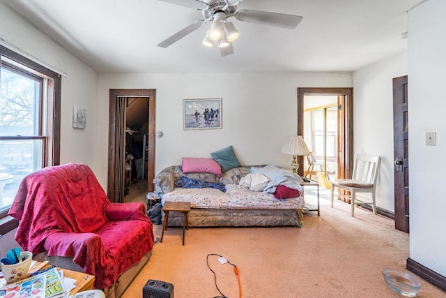 living area featuring carpet, ceiling fan, plenty of natural light, and baseboards