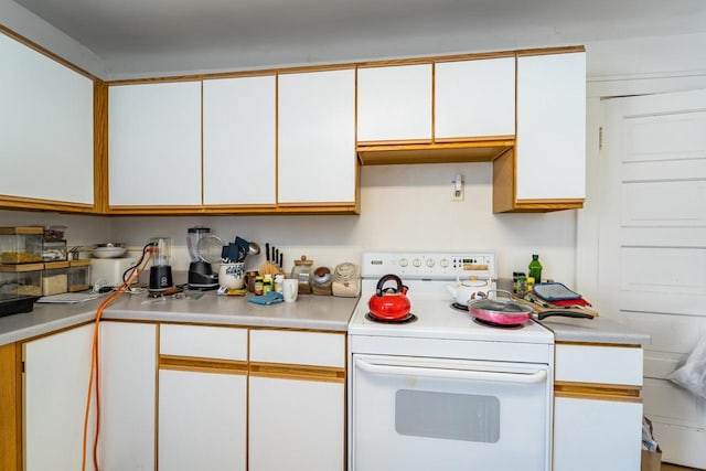 kitchen featuring electric stove, light countertops, and white cabinets