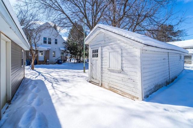 snow covered structure featuring an outbuilding