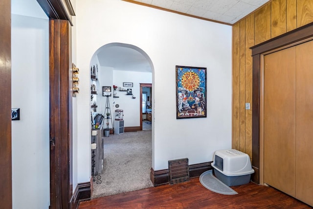 hall featuring arched walkways, dark colored carpet, and dark wood finished floors