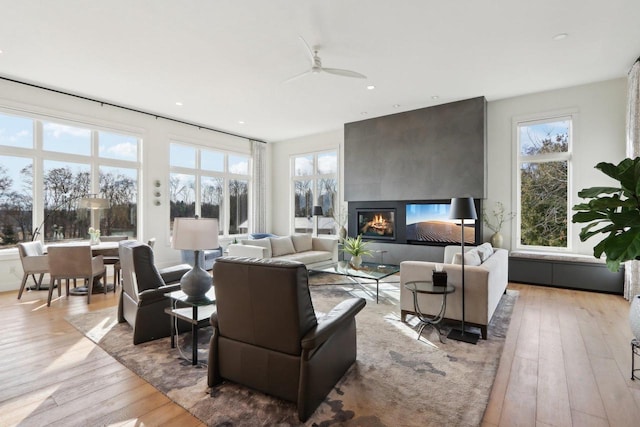 living room featuring light wood finished floors, a large fireplace, a wealth of natural light, and recessed lighting