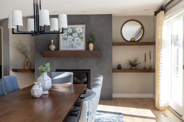 dining room featuring light wood-style floors, visible vents, baseboards, and a large fireplace