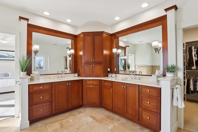 bathroom with double vanity, a sink, a walk in closet, and recessed lighting