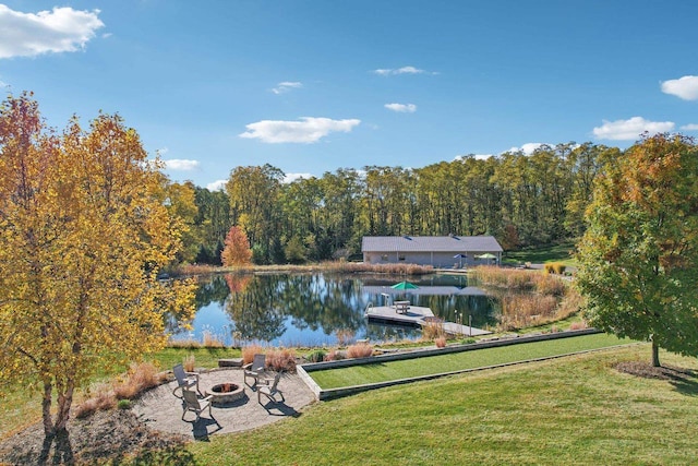 view of home's community featuring a water view, an outdoor fire pit, a lawn, and a boat dock