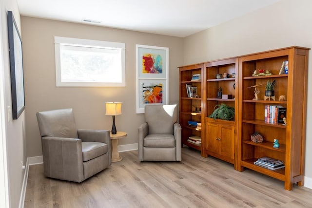 sitting room featuring light wood-style floors, visible vents, and baseboards