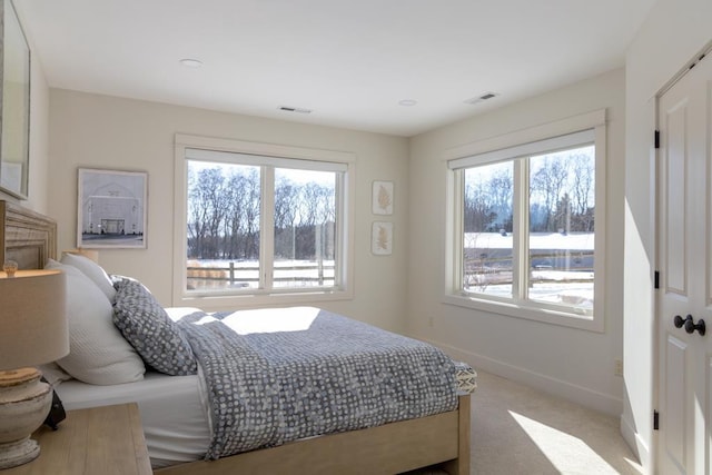 bedroom with light carpet, visible vents, multiple windows, and baseboards