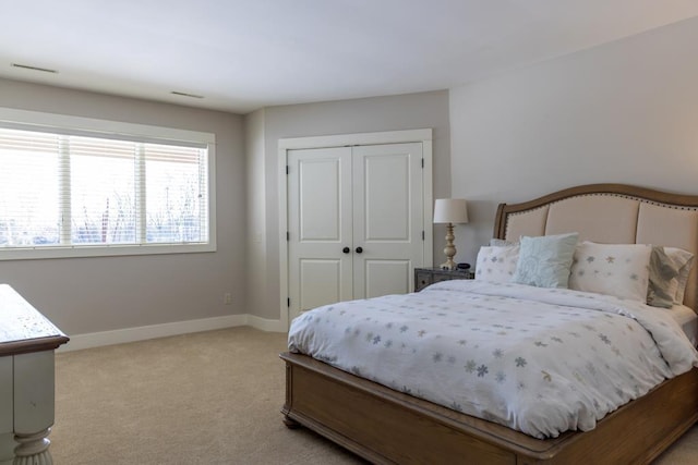 bedroom with visible vents, baseboards, a closet, and light colored carpet