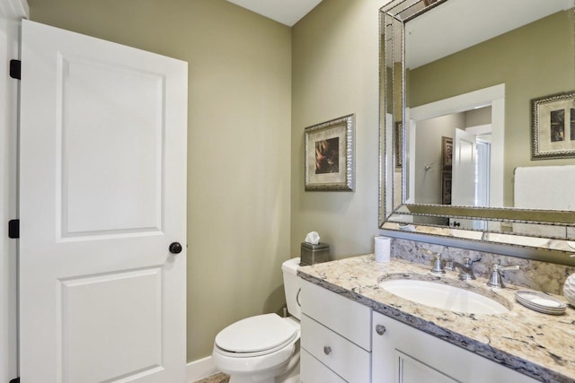 half bathroom featuring toilet, vanity, and baseboards