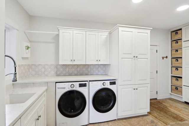 laundry area featuring cabinet space, a sink, light wood-style flooring, and washing machine and clothes dryer