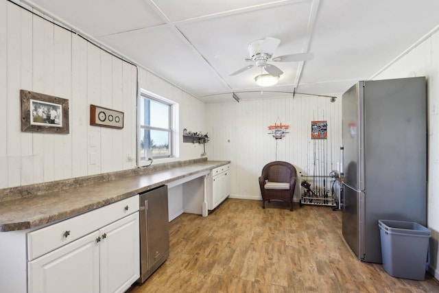 kitchen featuring white cabinets, dark countertops, wood finished floors, freestanding refrigerator, and fridge