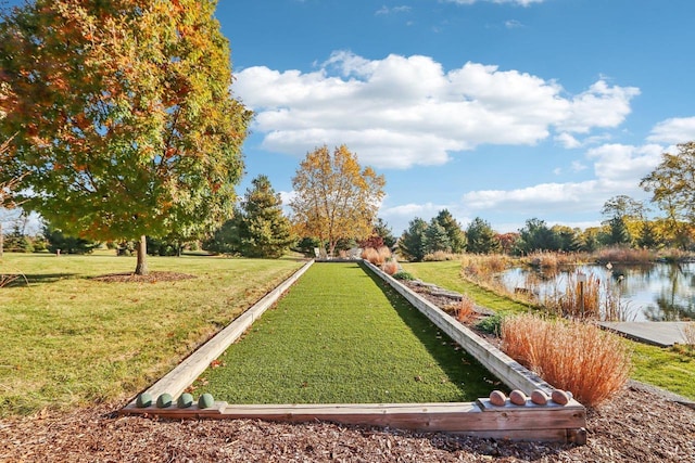 view of home's community with a water view and a lawn