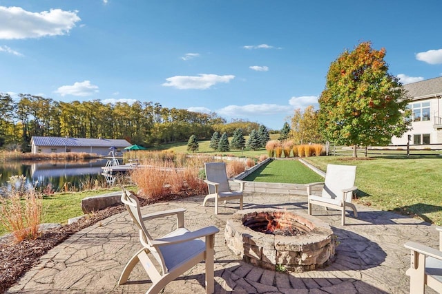 view of patio featuring a water view, an outdoor fire pit, and fence