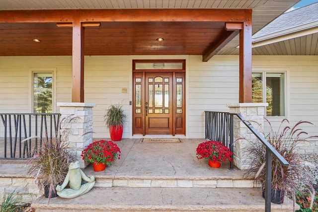 doorway to property with a porch and a shingled roof