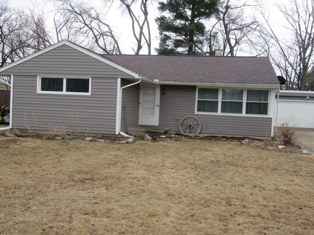 ranch-style house with a garage, roof with shingles, and a front yard