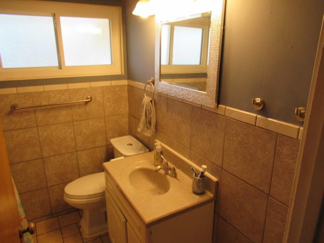 bathroom with toilet, tile patterned flooring, tile walls, and vanity