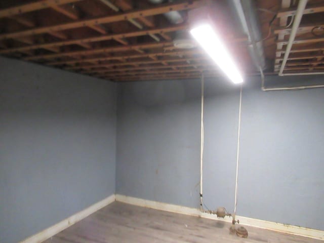 basement with baseboards and wood finished floors